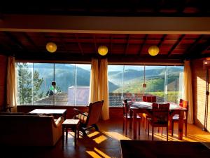 a living room with a table and chairs and a large window at Chalé Ganesh - O chalé é maravilhoso! in Cunha