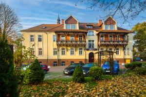 una grande casa con macchine parcheggiate di fronte di Willa Diament a Kudowa-Zdrój