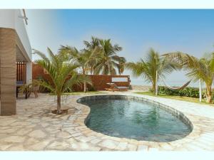 uma piscina num quintal com palmeiras em beachhouse MIMA em Saly Portudal