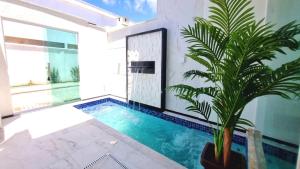 uma piscina no meio de uma casa com uma planta em Apartamento a 400 metros da praia de taparapuan em Porto Seguro