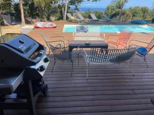 a bbq and some chairs and a table and a pool at Villa Jujubes in Le Bois de Nèfles
