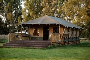 a tent with a wooden porch in a field at Horsley Hale Farm Glamping in Ely