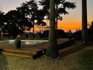 a swimming pool with two palm trees and a sunset at Villa Jujubes in Le Bois de Nèfles