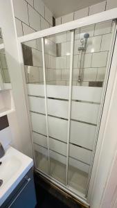 y baño con ducha y puerta de cristal. en LA VILLA DEKO - Studio avec parking proche Université et Hôpital, en Beuvry