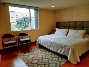 a bedroom with a bed and two chairs and a window at Hotel Morasurco in Pasto