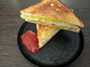 a sandwich on a black plate with ketchup at Cosmos @ Greenspace in Siolim
