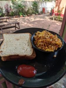 a black plate with a sandwich and a bowl of food at Cosmos @ Greenspace in Siolim