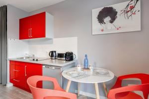 una cocina con armarios rojos y una mesa pequeña con sillas rojas. en Annecy Studio balcony close to old town, en Annecy