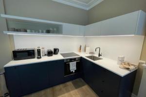 a kitchen with blue cabinets and a sink and a microwave at Central 1 Bedroom Apartment in Farringdon in London