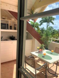 a balcony with a table and chairs and a kitchen at Studio Kowosol en résidence de vacances in Sainte-Anne
