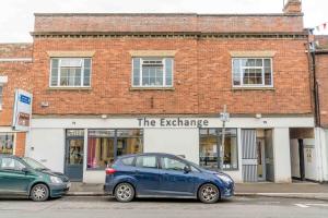 un coche azul estacionado frente a un edificio de ladrillo en The Exchange Apartments with Permit Parking, en Tewkesbury