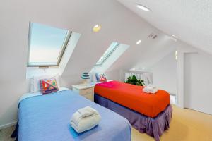 two beds in a attic bedroom with two windows at Great Lakes 49 50 in Glen Arbor