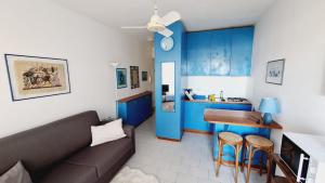 un salon avec un canapé et une cuisine avec des armoires bleues dans l'établissement Apartment in Residence BaiaSole, à Sanremo