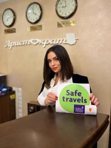 une femme assise à une table avec un signe de voyage sûr dans l'établissement Aristokrat, à Vinnytsia