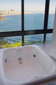 a white bath tub sitting in front of a window at Beach Loft next to the Sheraton Leblon in Rio de Janeiro