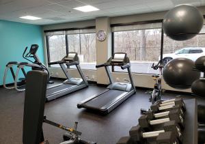 a gym with several tread machines and a clock at avid hotels - Salem, an IHG Hotel in Salem