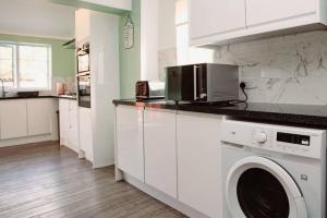 a white kitchen with a washing machine in it at Cozy 3-Bedroom Home in Luton in Luton