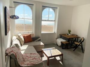 a living room with a couch and a table and two windows at Spacious 2BD Flat with Stunning Views Folkestone in Folkestone
