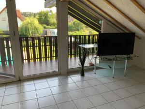 un porche cubierto con TV y mesa en Apartment und Ferienwohnung Mackenbach, en Mackenbach