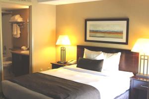 Cama en habitación de hotel con 2 lámparas y teléfono en Franklin Suite Hotel en Fort McMurray