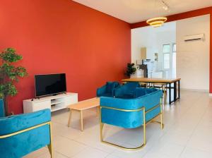 a living room with blue chairs and a television at Brand New Cozy home Desaru Pengerang near Sebana Cove Resort in Pengerang