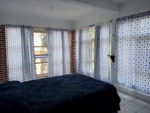 Casa amplia en Cuernavaca في كويرنافاكا: غرفة نوم مع ستائر زرقاء وبيضاء وسرير