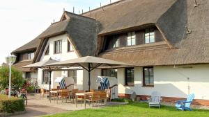 ein Haus mit Stühlen, Tischen und einem Sonnenschirm in der Unterkunft Mare Balticum Urlaub auf Rügen in Sagard