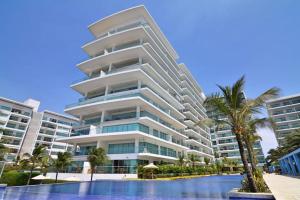 a large apartment building with a swimming pool and a palm tree at Apartamento de lujo en Morros Ultra in Cartagena de Indias