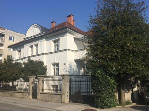 a white house with a fence in front of it at House Elza in Ljubljana