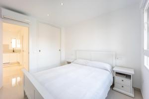 ein weißes Schlafzimmer mit einem Bett und einem Nachttisch in der Unterkunft Premium apartment in Benidorm + 14 Fotos