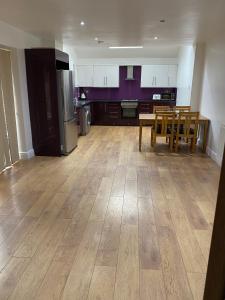 a kitchen with a wooden floor and a table and chairs at BIG ROOM rusholme WITH TV AND PRIVATE BATHROOM-parking&wifi in Manchester