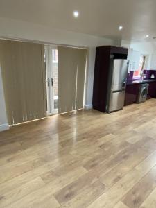 an empty living room with wooden floors and a refrigerator at BIG ROOM rusholme WITH TV AND PRIVATE BATHROOM-parking&wifi in Manchester