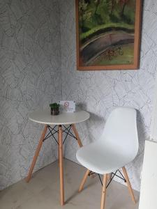 a table and a white chair next to a wall at La Sierra Guest House in Manbiga
