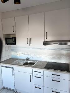 eine Küche mit weißen Schränken und einem Waschbecken in der Unterkunft Appartment 43 Haus Spiekeroog in Dornumersiel
