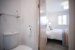 a white bathroom with a toilet and a bed at Minarvon - 2 Bedroom Apartment - Saundersfoot in Saundersfoot +33 photos