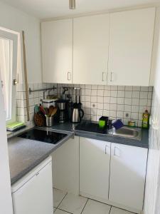 una cocina con armarios blancos y fregadero en Exklusiv möblierte Wohnung in besten Lage, en Stuttgart