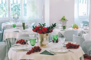 uma sala de jantar com mesas brancas com rosas vermelhas num vaso em Eveline Portosole Hotel em Sanremo