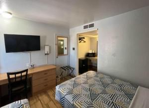 een slaapkamer met een bed, een bureau en een televisie bij Motel 6 Riviera Beach FL in Riviera Beach