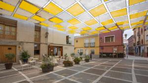 un cortile con tavoli e sedie e un soffitto giallo e bianco di Casa rural Plaza Vieja en Bullas a Bullas