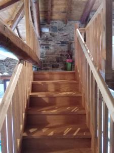 a wooden staircase in a house with a stone wall at CASA EL TEIXO in Taramundi