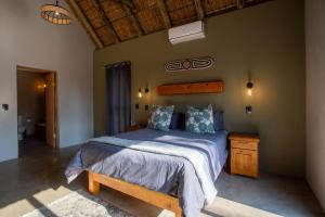 a bedroom with a bed with a blue comforter at Vuyani Marula Lodge in Hoedspruit