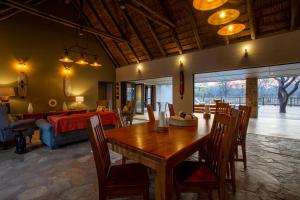 a dining room with a table and a living room at Vuyani Marula Lodge in Hoedspruit