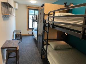 Cette chambre comprend des lits superposés, une table et un banc. dans l'établissement Northwest Portland Hostel, à Portland