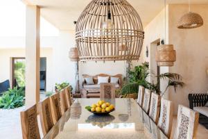ein Esszimmer mit einem Tisch und Stühlen sowie einer Obstschale in der Unterkunft Lavish Ibizan Villa Beautiful Gardens Villa Izarra Located Between San Antonio and San Jose in Cala de Bou