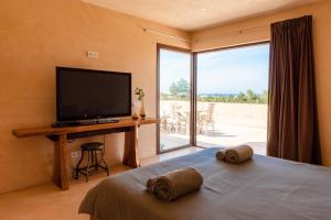 Schlafzimmer mit einem Bett, einem TV und einem Balkon in der Unterkunft Lavish Ibizan Villa Beautiful Gardens Villa Izarra Located Between San Antonio and San Jose in Cala de Bou