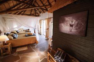 Un dormitorio con una cama y un televisor en una pared. en Huab Lodge & Bush Spa, en Konob Pos