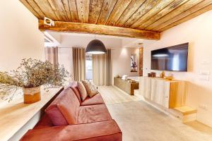 ein Wohnzimmer mit einem braunen Sofa und einem TV in der Unterkunft Praia Art Resort - Small Luxury Hotels of the world in Le Castella