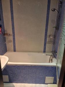 a bathroom with a white tub and blue tiles at Apartment Maya in Visaginas