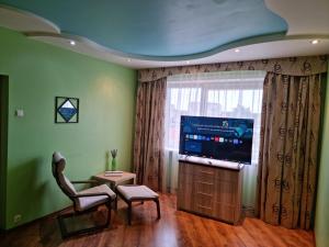 sala de estar con TV, silla y ventana en Apartment Maya, en Visaginas