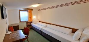 イシュグルにあるHotel Garni Belvedereのベッド2台とテーブルが備わるホテルルームです。